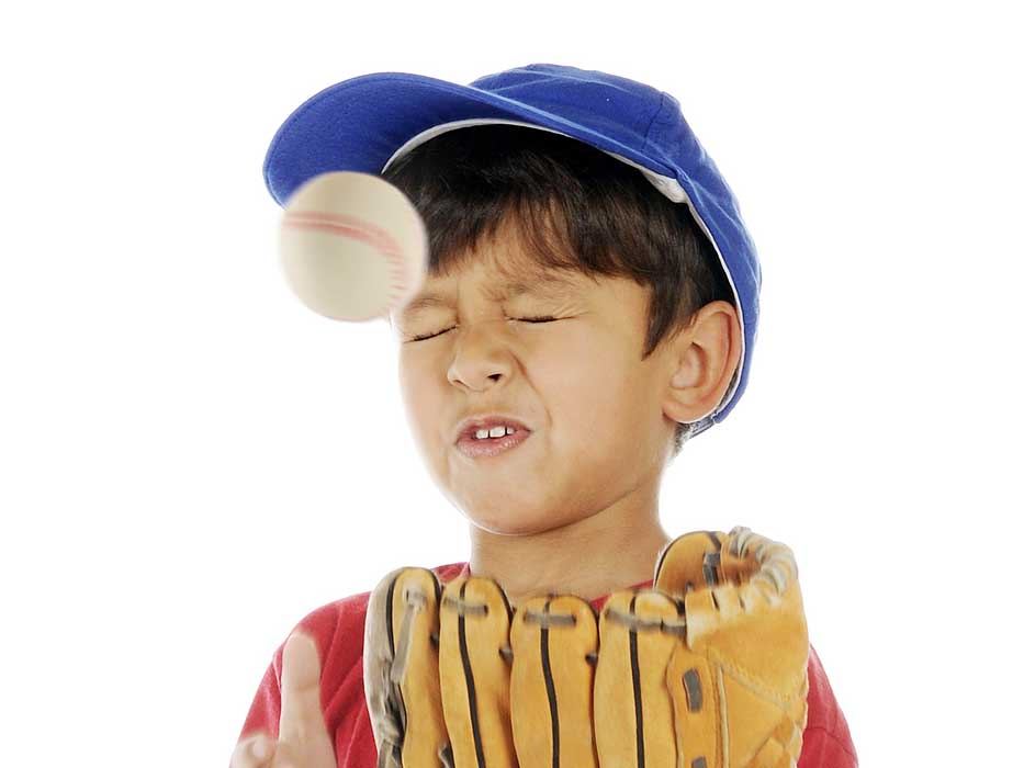 An adorable preschooler making a face while getting bonked by a baseball
